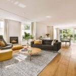 Contemporary minimalist style interior design of light studio apartment with wooden table and chairs in dining zone between open kitchen and living room with white walls and parquet floor