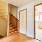 White hallway with wooden stairway leading to second floor of modern luxury apartment with minimalist interior design